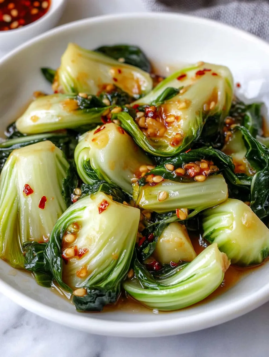 A bowl of greens with a sauce on top.