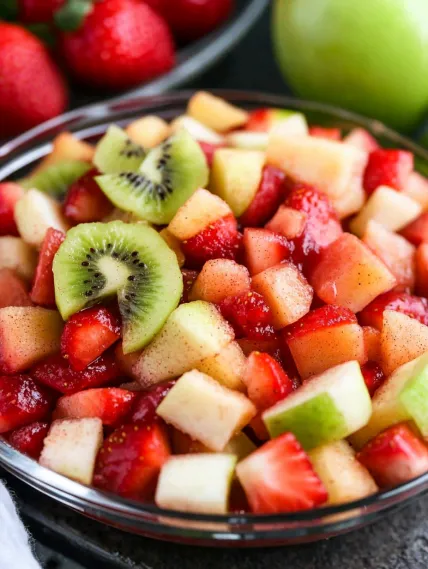 A bowl of fruit with kiwi, strawberries, and apples.