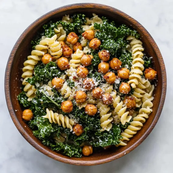 A bowl of pasta paired with roasted chickpeas and fresh greens.