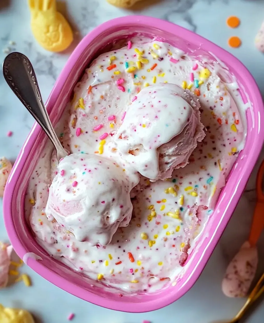 A pink bowl of ice cream with sprinkles.