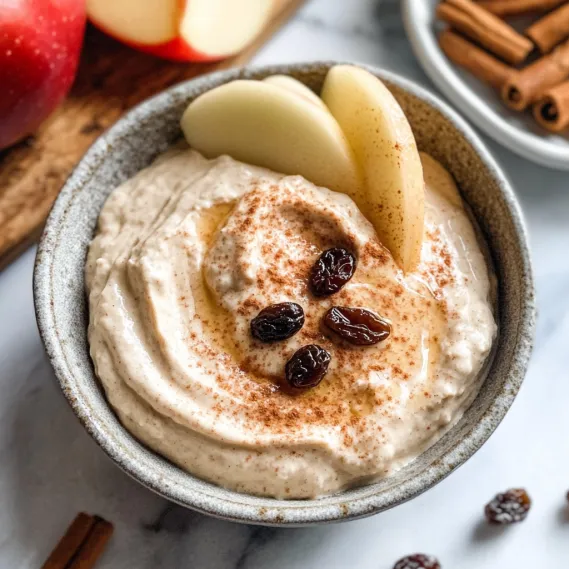 A bowl of dip garnished with raisins and cinnamon.