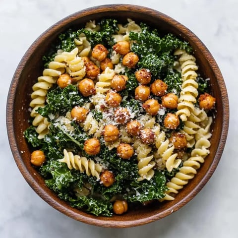 A bowl of pasta paired with roasted chickpeas and fresh greens.